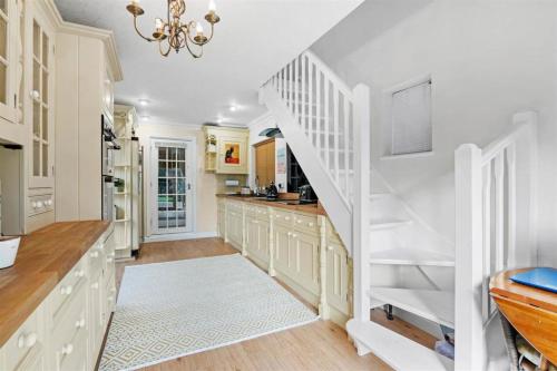 a kitchen with white cabinets and a white staircase at The Corner House, 36, Broadway Road, in Evesham