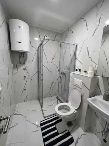 a white bathroom with a toilet and a sink at Apartment A20 in Novi Sad