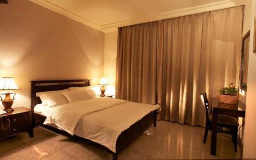 a bedroom with a bed and a desk and a window at Tamrah Suites Hotel in Amman