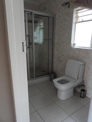 a bathroom with a toilet and a glass shower at Executive apartment with 2 beds kitchenette - 2072 in Harare