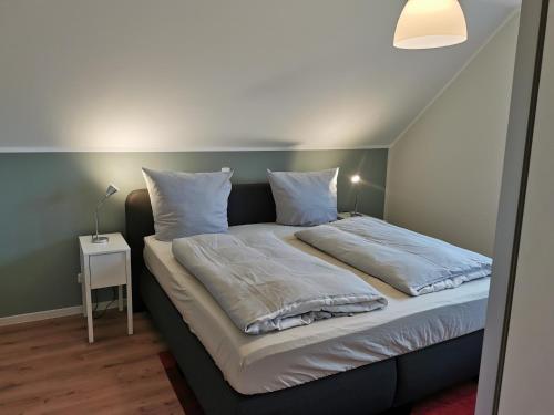 Bett mit weißer Bettwäsche und Kissen in einem Zimmer in der Unterkunft FeWo Wiardergroden - Horumersiel in Horumersiel