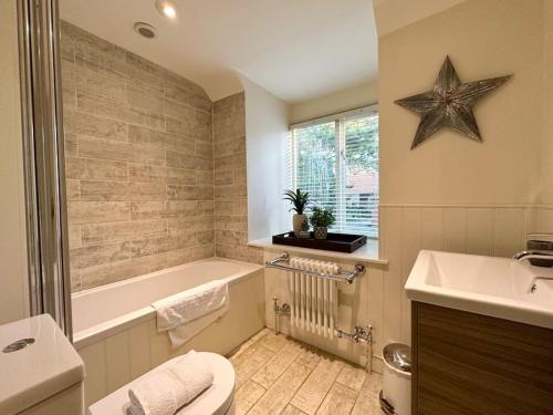 a bathroom with a tub and a toilet and a sink at NEW! Blakeney. Harbour View in Blakeney