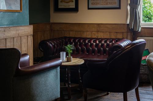 a leather couch in a bar with a table and chairs at Three Tuns in Helston