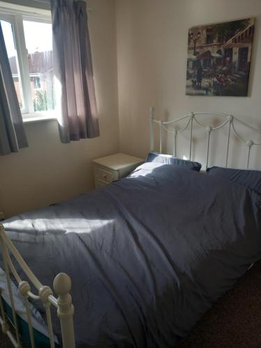1 dormitorio con 1 cama con edredón azul y ventana en 32 Elder Drive Chester CH4 8PD en Chester