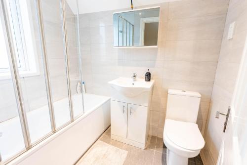 a white bathroom with a toilet and a sink at Beautiful 3 bedroom house, Ashbnhm,Luton free parking in Luton