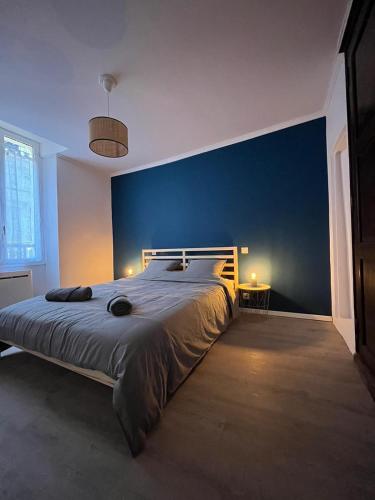 une chambre avec un grand lit avec un mur bleu dans l'établissement Les Vans - Charmant appartement au cœur du village, aux Vans