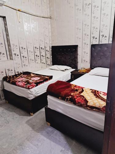 Lords Hotel في لاهور: سريرين في غرفة مع سريرين sidx sidx