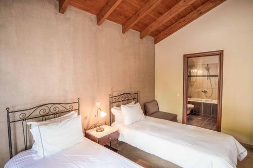 Un dormitorio con dos camas y un baño. en Apolis Luxury Villa, en Agios Georgios