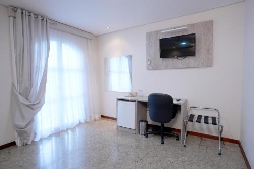 a room with a desk and a chair and a window at Colonial Plaza Hotel Pindamonhangaba in Pindamonhangaba