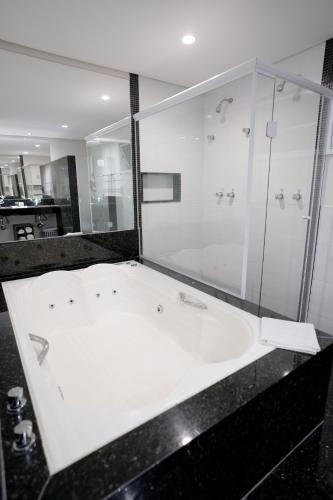 a bathroom with a shower and a white sink at Colonial Plaza Hotel Pindamonhangaba in Pindamonhangaba