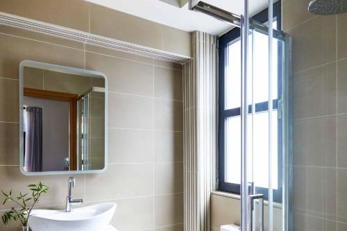 un bagno con un lavandino, uno specchio e una finestra di Villa Andriana Karvouno Villas a Sivota