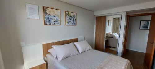 um quarto com uma cama e duas fotografias na parede em Recanto Terraneo-Gramado em Gramado