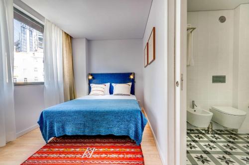 a bedroom with a blue bed and a bathroom at Lisbon Serviced Apartments - Liberdade in Lisbon