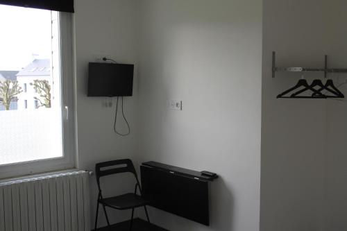 Habitación con silla y TV en la pared. en Hôtel et Restaurant de la Gare Torigny-les-Villes, en Torigni-sur-Vire