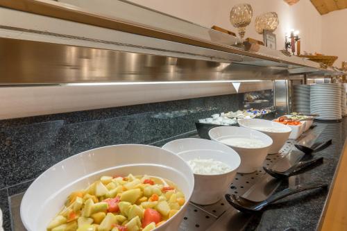 a buffet line with bowls of food on a counter at BSW Hotel Hubertus-Park in Schönau am Königssee