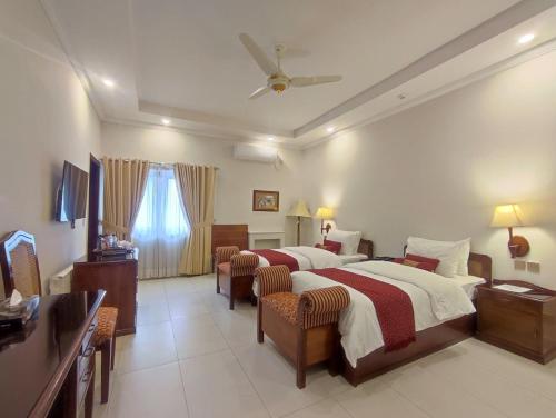 um quarto de hotel com duas camas e duas cadeiras em Welcome Hotel Islamabad em Islamabad