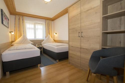 um pequeno quarto com 2 camas e uma cadeira em Gästehaus Koch em Fischen