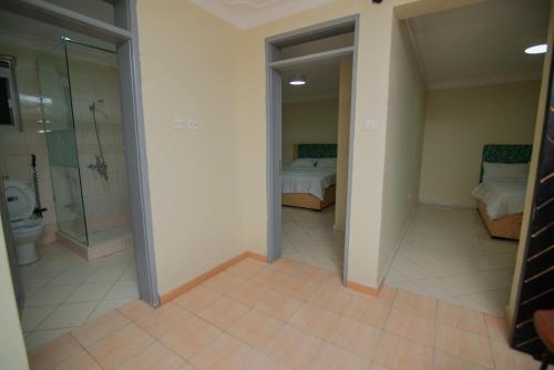 a large bathroom with a shower and a bedroom at Olori Flats in Munyonyo
