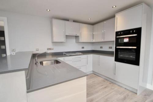 a white kitchen with white cabinets and a black appliance at 3 bedroom barn conversion in the country (Pet Friendly) in Stawell