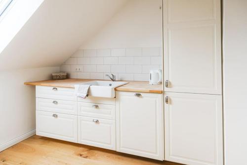 una cocina con armarios blancos y fregadero en Ferienwohnung Stylo 2.0 en Celle