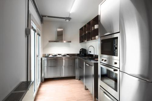 a kitchen with stainless steel appliances and a wooden floor at BasicVillage Milano in Milan