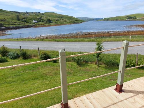a wooden deck with a fence and a body of water at The Causeway in Bracadale