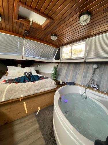 - une chambre avec une baignoire à côté d'un lit dans l'établissement Bateau Fellowship, à Narbonne