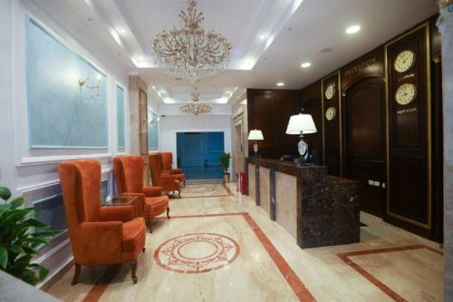 a lobby with orange chairs and a chandelier at The Guard Hotel in Cairo