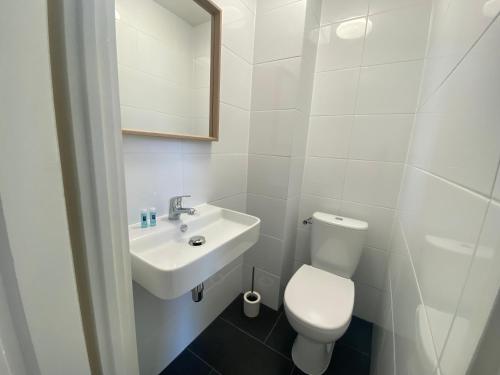 ein weißes Bad mit einem WC und einem Waschbecken in der Unterkunft Hotel 't Sonnehuys in Scheveningen
