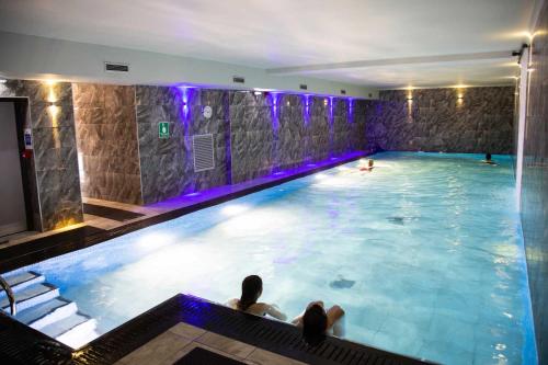 basen z dwoma osobami siedzącymi w nim w obiekcie Biskey Howe flat - FREE off-site Health Club access with Pool, Sauna, Steam Room & Gym w mieście Windermere