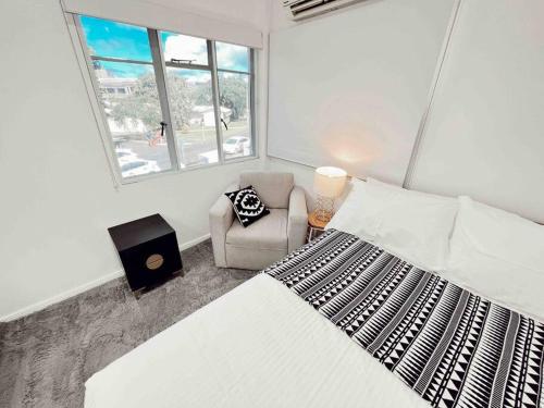 a bedroom with a bed and a chair and a window at Gladestone Gem 2 - Suva CBD - 2bd Apt in Suva