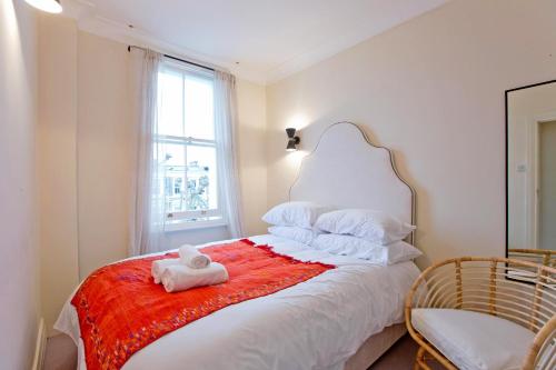 a white bed with a stuffed animal on a red blanket at 4 Bed Duplex Garden Views in London
