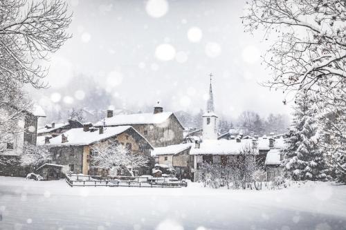 a village covered in snow with a church at Auberge de La Maison in Courmayeur