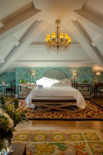 a bedroom with a large bed and a chandelier at A Quinta Da Auga Hotel Spa Relais & Chateaux in Santiago de Compostela