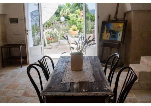 Masseria Verbena Agriturismo في مونوبولي: طاولة خشبية عليها كراسي و مزهرية