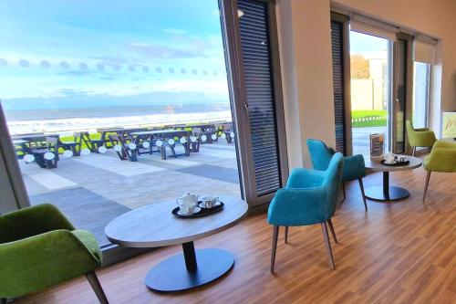 a room with chairs and tables and a view of the beach at Caban, Pendine Sands in Pendine