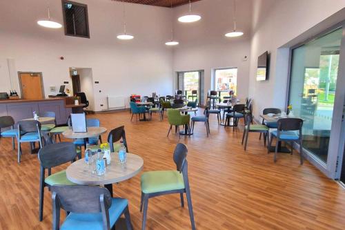 a restaurant with tables and chairs in a room at Caban, Pendine Sands in Pendine