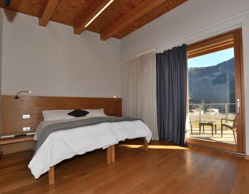 ein Schlafzimmer mit einem Bett und einem großen Fenster in der Unterkunft Agritur Anselmi in Terzels