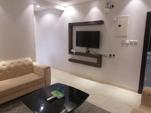 a living room with a couch and a tv on a wall at العرين بارك للشقق المخدومة in Abha