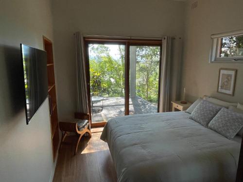 - une chambre avec un lit et une porte coulissante en verre dans l'établissement Tranquil Garden Studio, à Wollongong