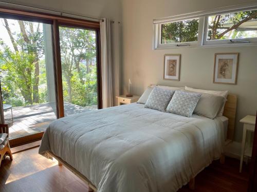 a bedroom with a bed and a large window at Tranquil Garden Studio in Wollongong
