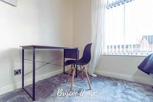 a desk with a chair in a room with a window at Briscoe Serviced Accommodation in Manchester