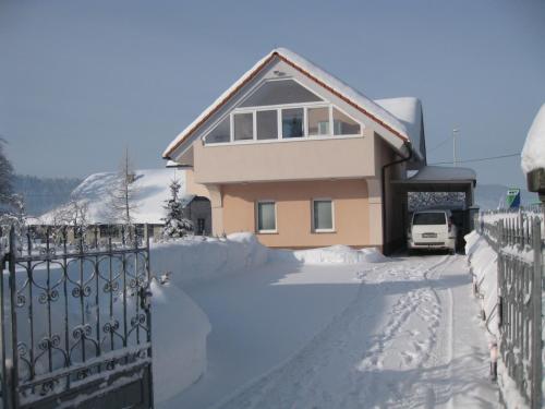 a house is covered in snow with a fence at Apartments Lavric in Nova Vas