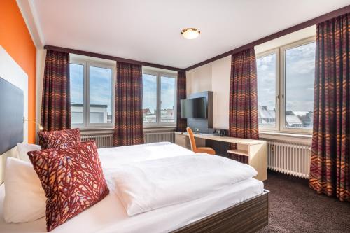 a hotel room with a bed and a tv and windows at Best Western Hotel Augusta in Augsburg