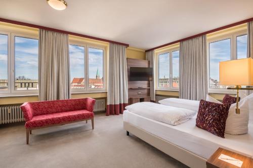 a bedroom with a bed and a chair and windows at Best Western Hotel Augusta in Augsburg
