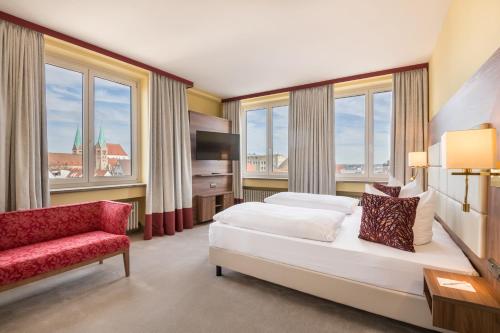 a bedroom with a bed and a chair and windows at Best Western Hotel Augusta in Augsburg