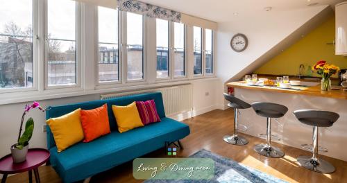 un sofá azul con almohadas coloridas en la sala de estar. en Cambridge Stays Diamond 2BR Apartment-Central-Parking-Walk to city & train station, en Cambridge