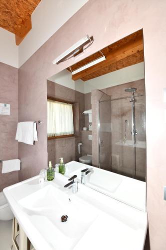 La salle de bains est pourvue d'un grand lavabo blanc et d'une baignoire. dans l'établissement Agritur Anselmi, à Terzolas