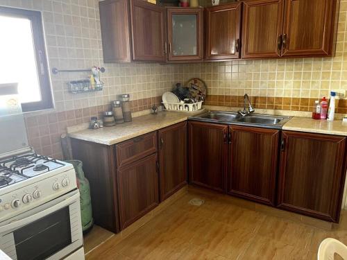 a kitchen with wooden cabinets and a stove and a sink at Madaba Hills Apt in Madaba