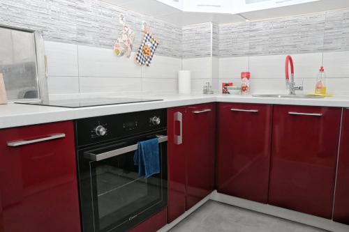 a kitchen with red cabinets and a black oven at Z&R SUNLIGHT in Trebinje